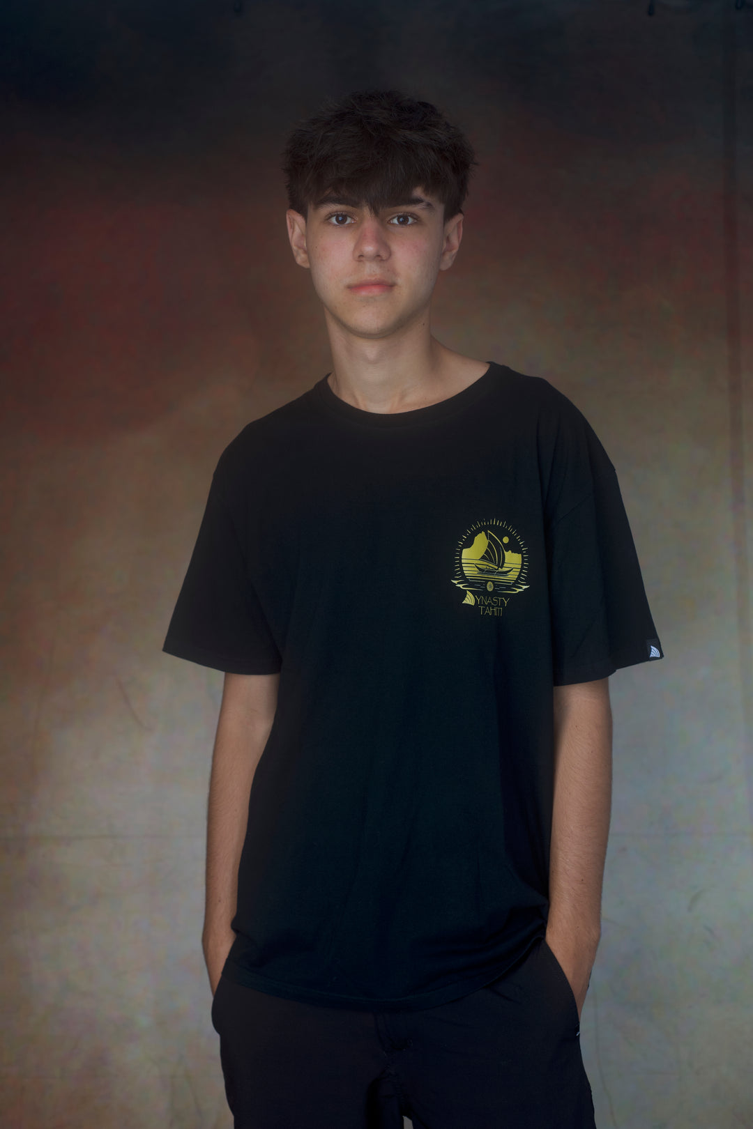 Person wearing a black t-shirt with a yellow logo against a plain background